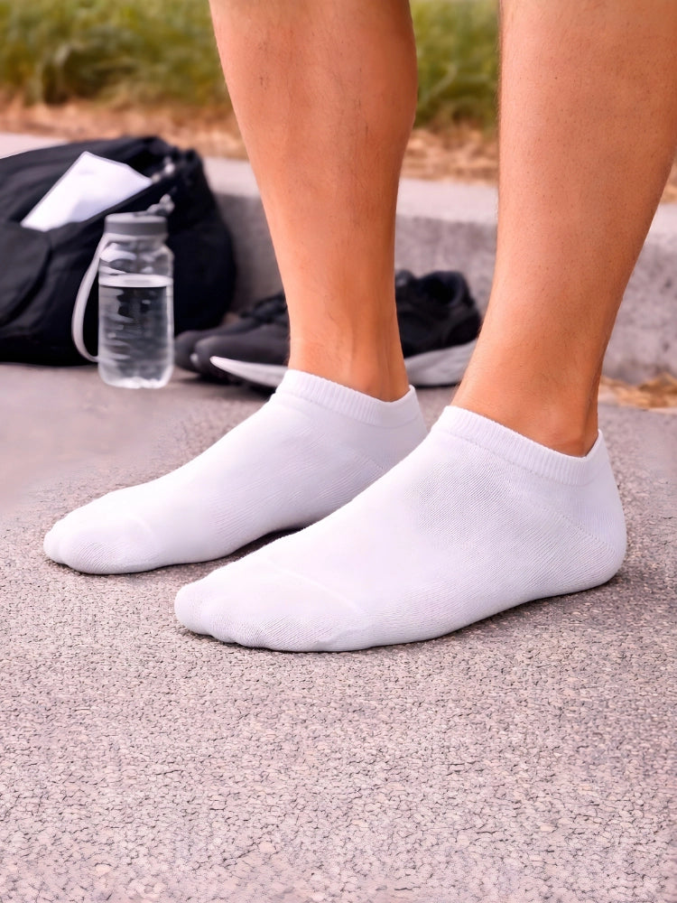 Person wearing white ankle socks with a blurred background of a road and backpack.

Men’s white trainer socks by Stylewar