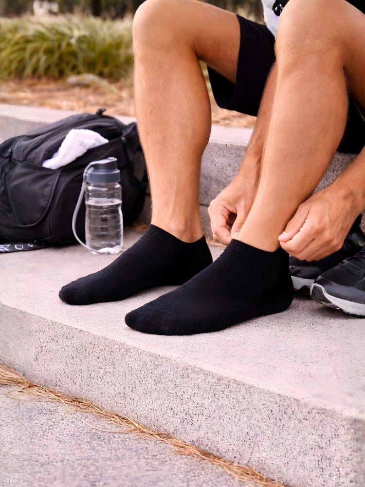 Person wearing black socks sitting outdoors with a water bottle and backpack.

Black men’s trainer socks for casual and activewear by Stylewar