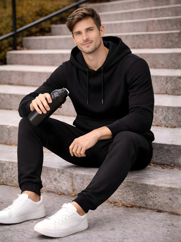 Man in black hoodie and pants sitting on steps holding a black bottle.

Men’s black pullover hoodie and jogger tracksuit set by Stylewar