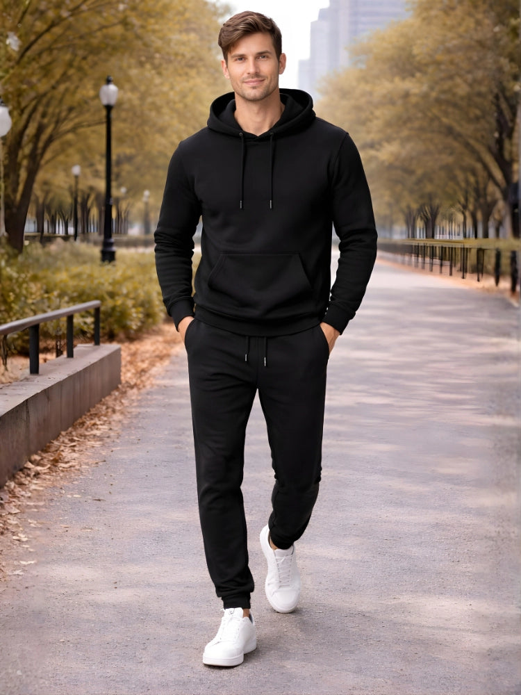 Man wearing a black hoodie and jogger pants standing on a path with trees and buildings in the background.

Black men’s pullover hoodie with matching jogger trousers by Stylewar