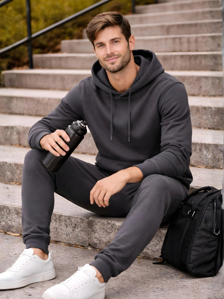 Man sitting on steps wearing a dark gray hoodie and pants, holding a water bottle.

Men’s dark grey pullover hoodie and jogger tracksuit set by Stylewar
