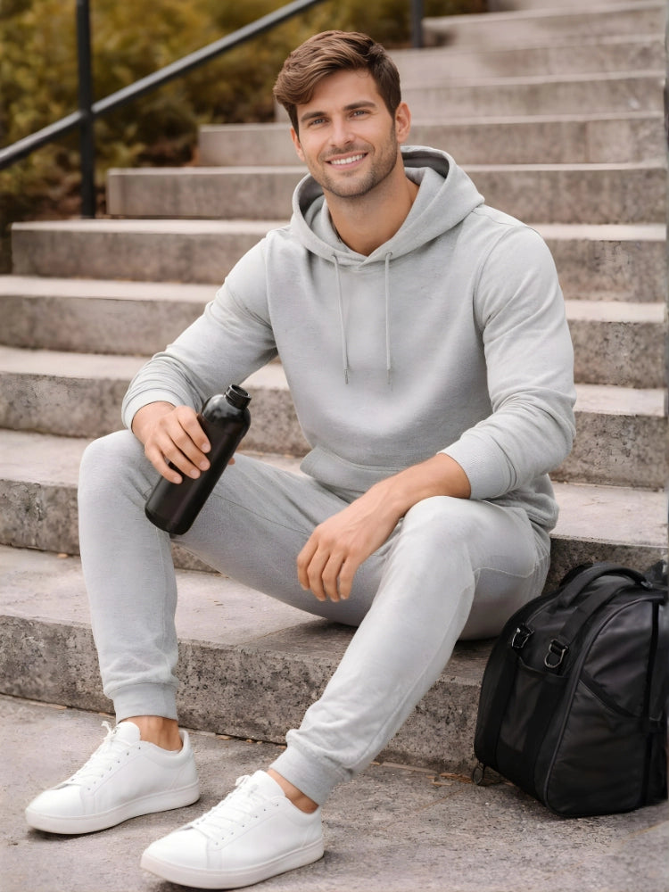 Man in gray hoodie and pants sitting on steps holding a water bottle.

Grey melange men’s pullover hoodie with matching jogger trousers by Stylewar