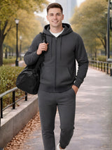 Man in dark gray hoodie and pants walking outdoors with a black bag.

Men’s dark grey zip hoodie and jogger tracksuit set by Stylewar