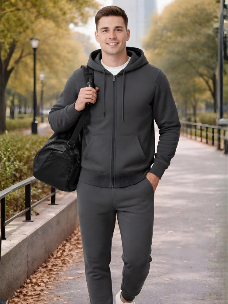 Man in dark gray hoodie and pants walking outdoors with a black bag.

Men’s dark grey zip hoodie and jogger tracksuit set by Stylewar
