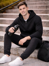 Man sitting on steps wearing a black hoodie and pants, holding a water bottle. 

Men’s black zip hoodie and jogger tracksuit set by Stylewar