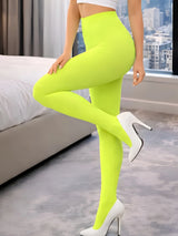 Person wearing bright green leggings and white high heels in a room with a cityscape view. Adult Crazy Chick Opaque Yellow Tights
