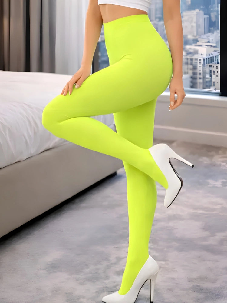 Person wearing bright green leggings and white high heels in a room with a cityscape view. Adult Crazy Chick Opaque Yellow Tights