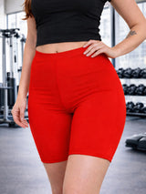 Person wearing red athletic shorts and a black top in a gym setting. Ladies Microfibre Red Cycling Shorts For Sports & Gym